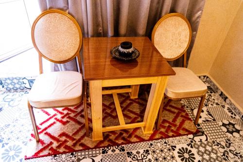 a wooden table with two chairs and a bowl on it at HOTEL LA VALLEE DES KASBAHS CHEZ ILYAS in Tinerhir