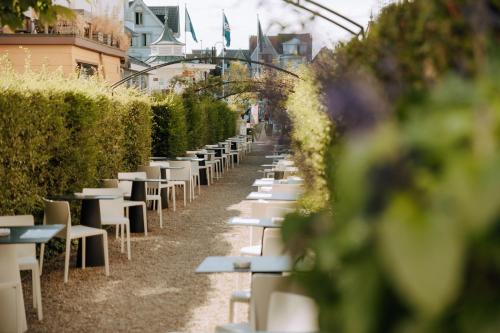 a row of tables and chairs in a garden at Hotel Astoria in De Haan