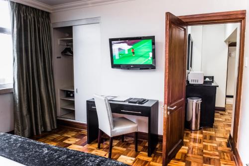 a room with a desk and a tv on the wall at Belaire Suites Hotel in Durban