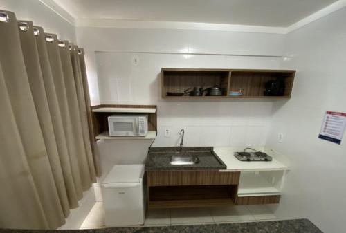 eine kleine Küche mit einer Spüle und einer Mikrowelle in der Unterkunft Lacqua diRoma com Parque Aquático e Cozinha in Caldas Novas