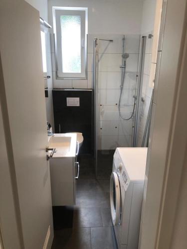 a bathroom with a sink and a washing machine at Ferienwohnung am Schölerberg in Osnabrück