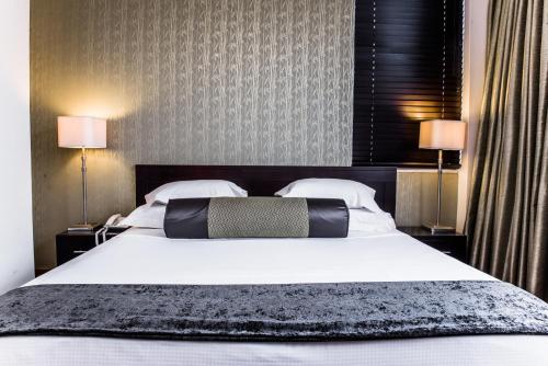 a bedroom with a large white bed with two lamps at Belaire Suites Hotel in Durban