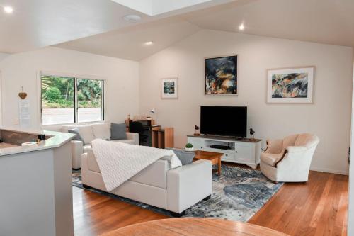 a living room with white furniture and a flat screen tv at Lake Russell Lakeside Retreat in Emerald Beach