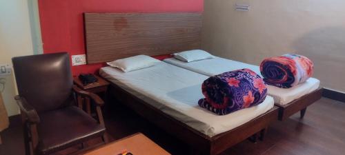 two twin beds in a room with a chair at Hotel Shiva Krishna(Unit of Nandan Udyam Pvt Ltd) in Patna
