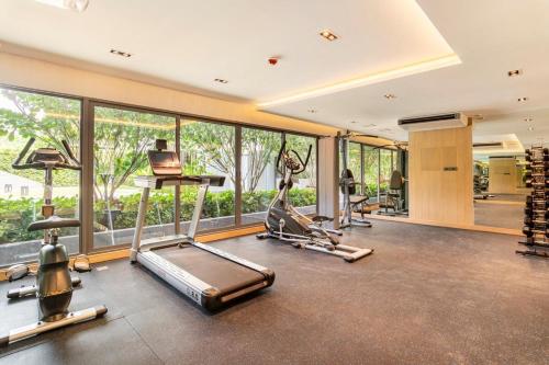 a gym with cardio equipment and large windows at Tierra Residences in Bangkok