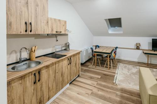 a kitchen with wooden cabinets and a sink and a table at Pansion "Fawlty Towers" Sarajevo in Sarajevo