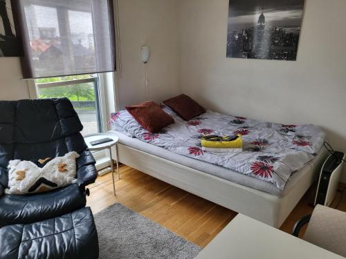 um pequeno quarto com uma cama e uma cadeira em One-room dorm with kitchenette, bath, bed 140x200 em Stavanger