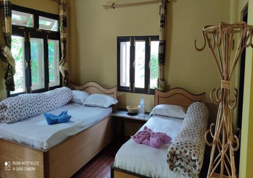 Tiger Land Homestay في Bhurkīā: سريرين توأم في غرفة مع نوافذ