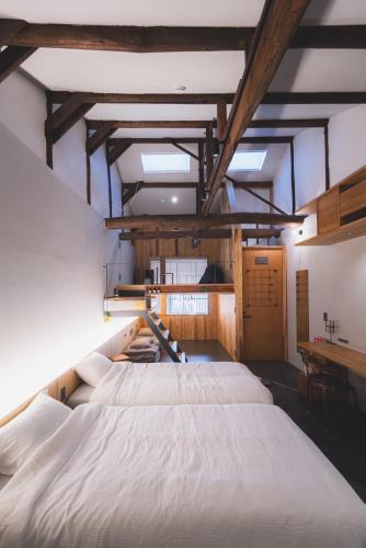 a large white bed in a room with wooden ceilings at ゲストハウス　遊楽２F in Osaka