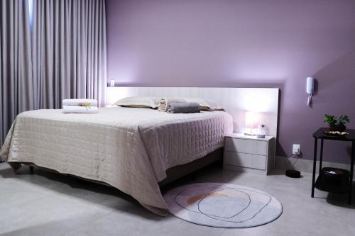 a bedroom with a large bed with purple walls at Moderno e Aconchegante Studio II in Belo Horizonte