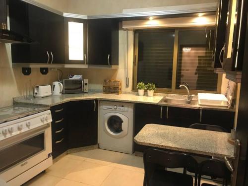 a kitchen with a sink and a washing machine at Modern two bedroom appartment in Amman