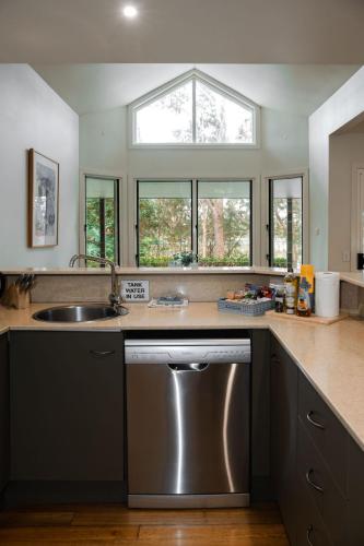 a kitchen with a stainless steel dishwasher and a sink at Lake Russell Lakeside Retreat in Emerald Beach