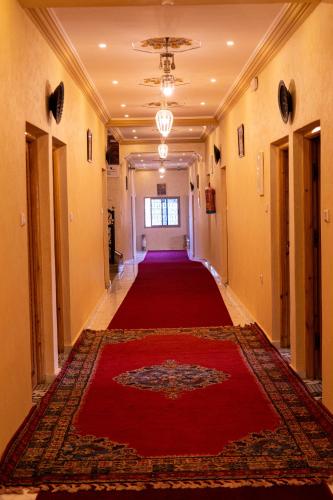 a hallway with a red carpet and a red rug at HOTEL LA VALLEE DES KASBAHS CHEZ ILYAS in Tinerhir