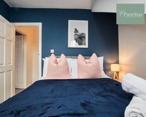 1 dormitorio azul con 1 cama grande con almohadas rosas en Fantastic Four Bedroom House By PureStay Short Lets & Serviced Accommodation Leeds With Parking, en Headingley