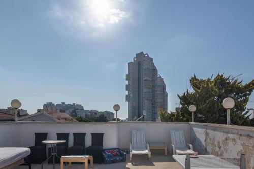 a rooftop with chairs and tables and a building at Luxury Villa 6BR with Swimming Pool by Beach - Villa Costa in Rishon LeẔiyyon