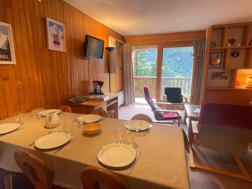 une salle à manger avec une table avec des chaises et une télévision dans l'établissement Appartement 2 pièces à Meribel, proche piste et commerces, avec parking et casier à ski - FR-1-411-717, à Les Allues