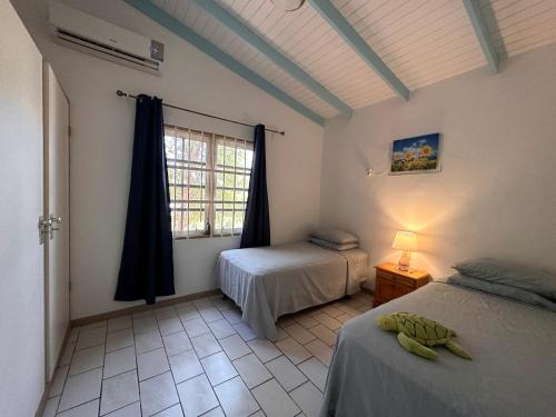 Club Seru Coral في فيليمستاد: غرفة نوم بسريرين ونافذة في غرفة