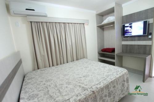 a small bedroom with a bed and a television at Lacqua diRoma com Parque Aquático e Cozinha in Caldas Novas