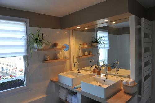 La salle de bains est pourvue de 2 lavabos et d'un grand miroir. dans l'établissement L'Appart Gîte de Charme, à Compiègne