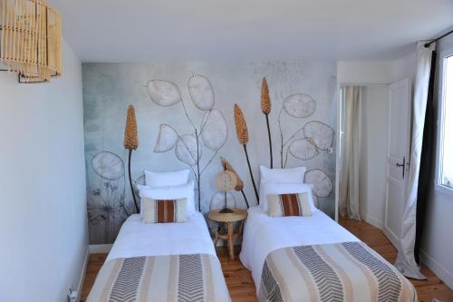 - 2 lits dans une chambre avec une fresque murale dans l'établissement L'Appart Gîte de Charme, à Compiègne