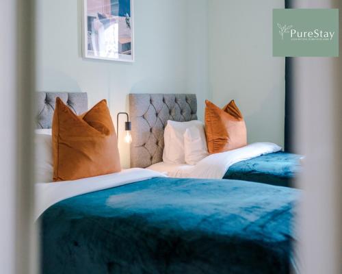 two beds in a bedroom with blue and orange pillows at Huge Four Bedroom Townhouse By PureStay Short Lets & Serviced Accommodation Bath in Bath