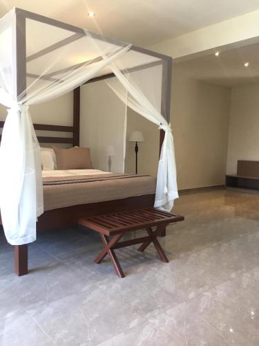 a bedroom with a canopy bed and a wooden bench at Waters Edge Liwonde in Liwonde