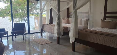 a bedroom with two beds and a view of the water at Waters Edge Liwonde in Liwonde