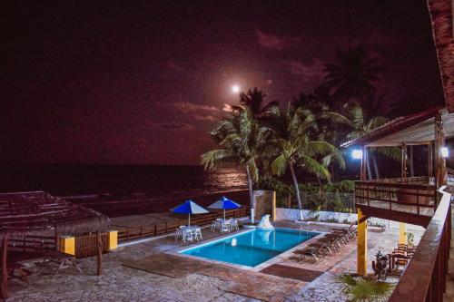 a swimming pool at night next to the ocean at Pousada Estrela da Luz Beach in Ceará-Mirim