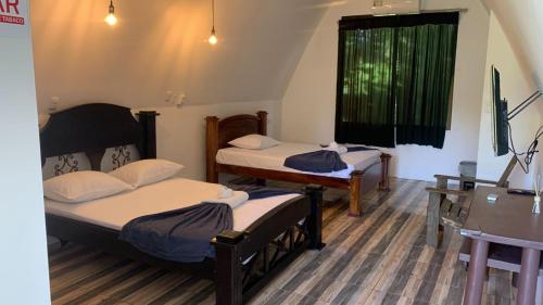 a room with two beds and a desk and a window at Eco Hotel Villas del Tortuguero in Cariari