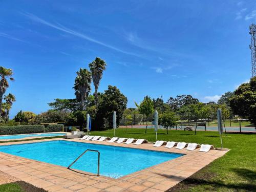 a swimming pool with lounge chairs next to a park at Castleton Self-Catering Accommodation in Plettenberg Bay