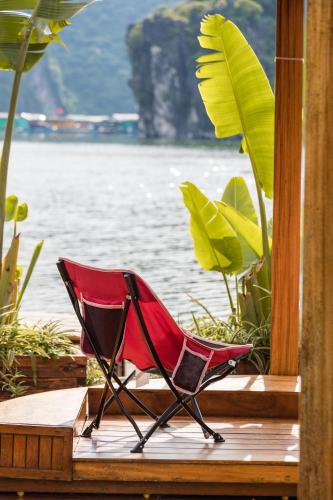 a red chair sitting on a deck near the water at Lan Ha Floating Homestay in Cat Ba