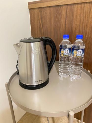 a tea kettle and two bottles of water on a table at Pi-thon In House in Yujing