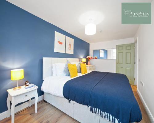 ein blaues Schlafzimmer mit einem großen Bett und gelben Kissen in der Unterkunft Stunning Two Bed Apartment By PureStay Short Lets & Serviced Accommodation Leamington With Free WiFi in Leamington Spa