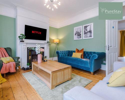 a living room with blue couches and a tv at Incredible Five Bedroom House By PureStay Short Lets & Serviced Accommodation Central Bath With Parking in Bath