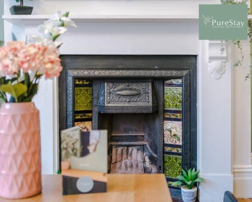 a fireplace in a living room with a vase of flowers at Incredible Five Bedroom House By PureStay Short Lets & Serviced Accommodation Central Bath With Parking in Bath