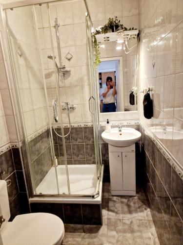 a man taking a picture of a bathroom with a shower at INNY Apartament Rynek Opole in Opole