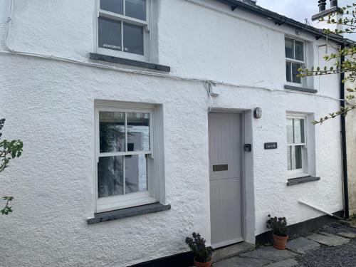 a white house with a door and two windows at Character Cottage Nr Betws Y Coed. in Betws-y-coed