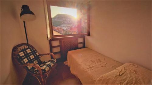 a room with a bed and a chair and a window at Casa PERLA panoramica 300m dal centro in Tagliacozzo