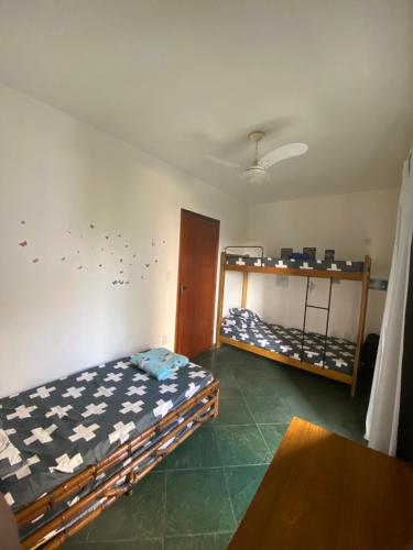 a bedroom with two bunk beds and a table at APARTAMENTO EM BERTIOGA in Bertioga