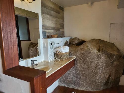 un bagno con lavandino e grande roccia di La Roca House a Praia do Rosa