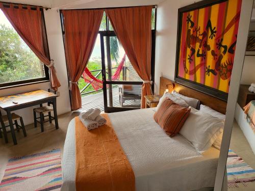 una camera da letto con un letto, un tavolo e una finestra di La Roca House a Praia do Rosa