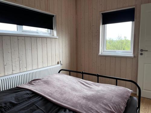 a bedroom with a bed and two windows at Ásólfsstaðir - Miðhóll in Ásólfsstaðir