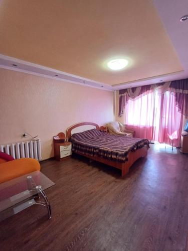 1 комнатная квартира остановка торговый центр في تشيركاسي: غرفة نوم بسرير في غرفة ذات أرضيات خشبية