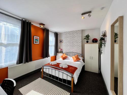 1 dormitorio con 1 cama con pared de color naranja en Clarence House 3 Bedrooms 8min to Station E17 North East London, en Londres