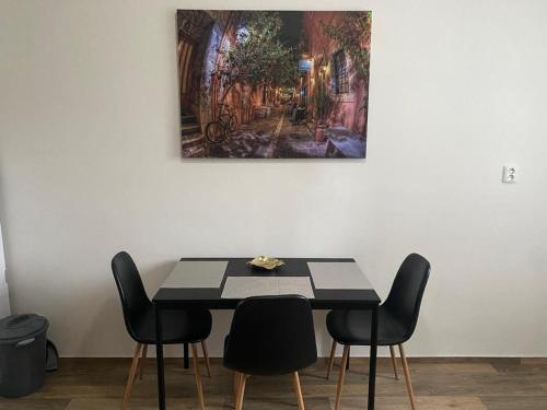 einen Esstisch mit Stühlen und ein Gemälde an der Wand in der Unterkunft Černá růže - Apartmán 4 in Pilsen