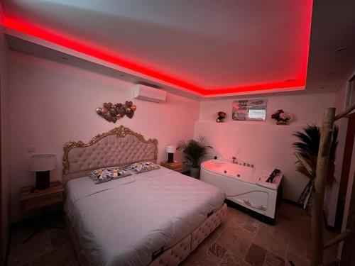 um quarto com uma cama e uma banheira com luz vermelha em L'Écrin de l'Amour em Saint-Avertin