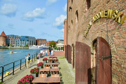 a brick building with tables and benches next to the water at Jess Krolewski Gdansk Old Town in Gdańsk