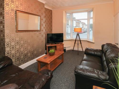 a living room with a leather couch and a television at 10 Walton Terrace in Guisborough