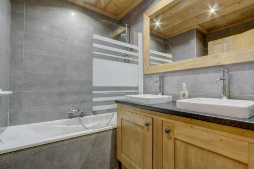 uma casa de banho com 2 lavatórios e uma banheira em CHEVRULS A4 em Morzine