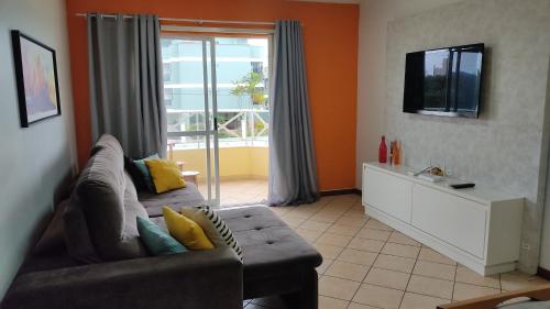 sala de estar con sofá y ventana grande en Apto 2 dormitórios, sendo 1suite a 350m da praia com churrasqueira, en Florianópolis